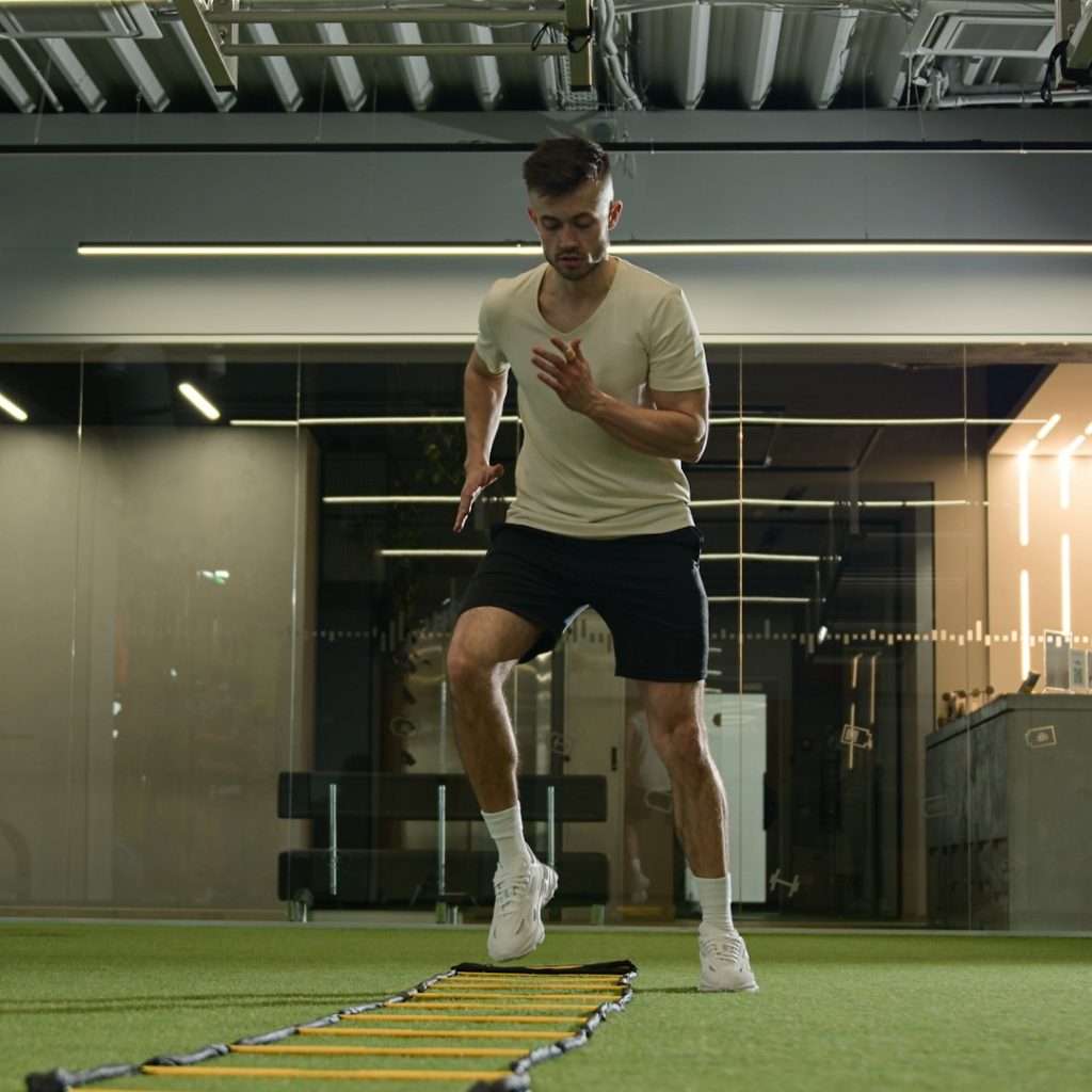 Caucasian sportsman man footballer soccer player training in sports gym exercise with ladder sport